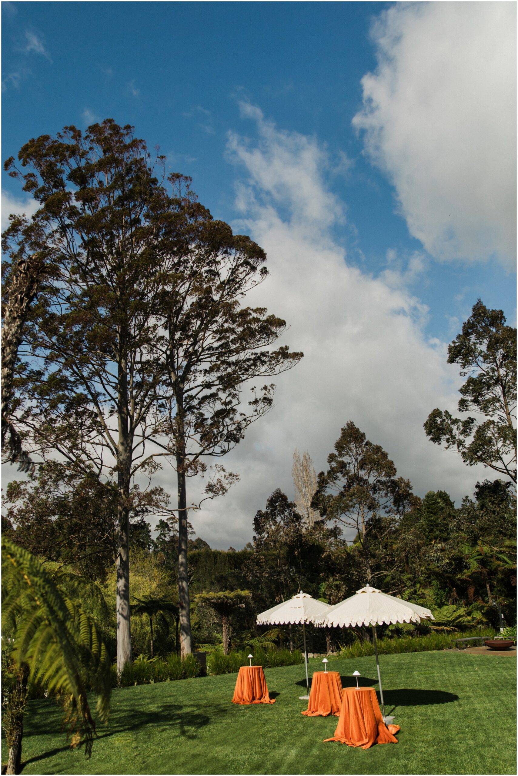 Outdoor wedding tablescape with scalloped umbrellas and orange velvet table